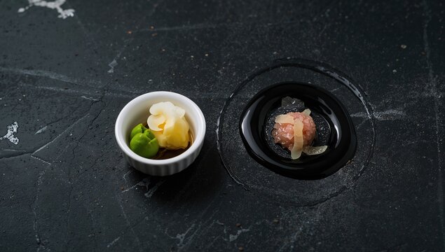 Sushi toppings and condiments arranged on a dark stone background, focusing on flavor enhancement methods