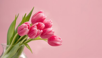 Vase filled with pink tulips against a pastel pink backdrop, suitable for spring invitations or floral display backdrops