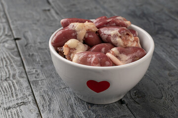 Raw Chicken Hearts in Heart-Adorned Bowl on Rustic Wooden Table