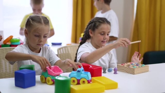 Child plays with toy and puzzle at bright classroom table showing girl and boy in preschool learning while child and friend play with colorful car block peg board and tabletop activity smile