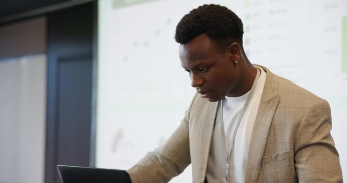 Sweating, speaker and man with stress, seminar and nervous with laptop for presentation or pressure. Public speaking, anxiety and black person with technology for speech, typing and worry for meeting