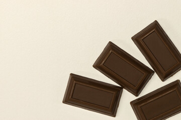 Milk chocolate squares pieces scattered on white background copy space.