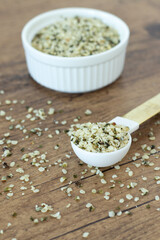 Hemp seeds in spoon on wooden table. Close-up. Healthy vegan protein food ingredient.