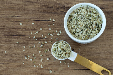 Organic hemp seeds in bowl and spoon on wooden background. Top view. Healthy vegan protein food.
