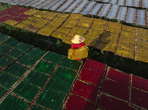 Aerial view of vibrant sheets of colorful rice paper drying in the sun, creating a stunning patchwork landscape, Tay Ninh, Tay Ninh, Vietnam.