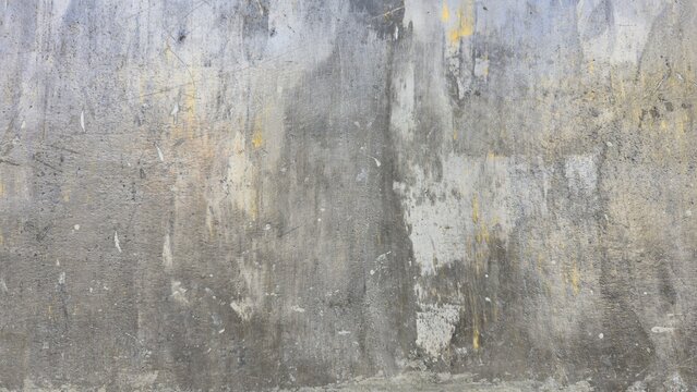 Distressed, old concrete wall texture of gray cement with cracks and peeling yellow paint. Features a vintage, grunge aesthetic and decay effect, ideal for backgrounds or design projects.