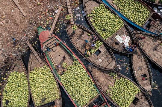 Aerial view of boats brimming with vibrant green watermelons jostle on murky waters, a lively river market scene from above, Dhaka, Dhaka Division, Bangladesh.