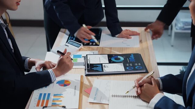 Corporate professionals collaborating on a business strategy, analyzing financial reports with charts and graphs on a digital tablet in the office