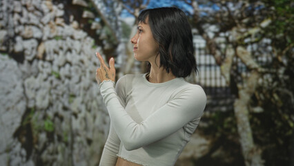 Young woman pointing finger with both hands while looking aside in lush green forest under soft daylight  confidence. © Krakenimages.com