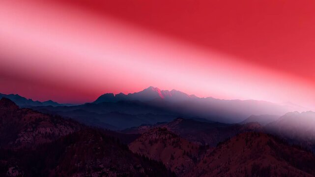 Wide view of majestic mountain landscape during sunset with gradient red and purple sky showcasing layers of peaks and soft light over rolling hills in natural outdoor setting