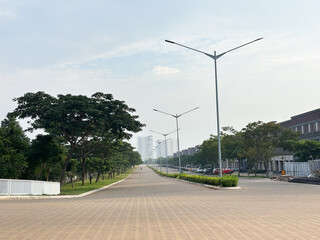 A wide-angle view of a modern, tree-lined avenue in an affluent urban residential or mixed-use development, likely in a developing Asian city.