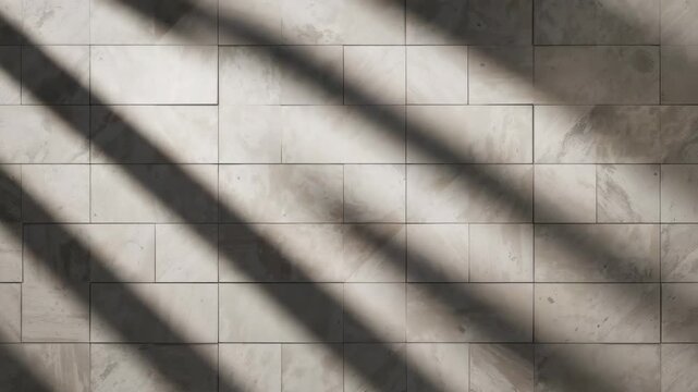 Close-up view of a light gray textured wall with varying tile patterns soft shadows gradually creeping across the surface capturing a serene indoor setting with natural light and minimal decor.