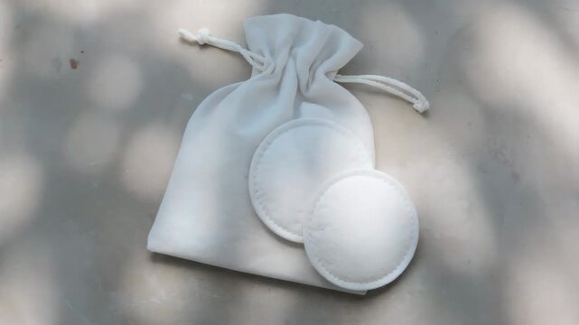 Reusable cotton facial pads and drawstring pouch on neutral background for eco-friendly skincare