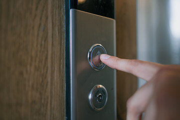 Human finger pushing up arrow button on elevator control panel, indicating starting journey, aiming for progress and growth, using modern technology for convenient transport