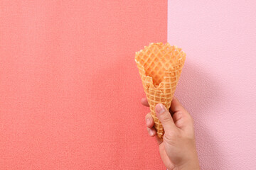 Hand Holding Empty Ice Cream Cone on Pink Background