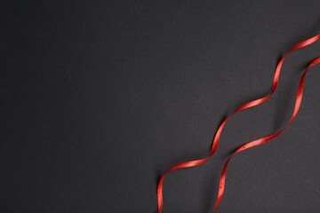 Beautiful red ribbons on dark background, top view. Space for text