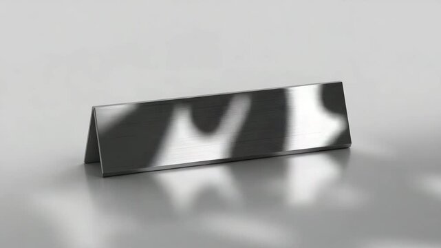 Brushed metal desk nameplate with moving abstract reflections on studio background