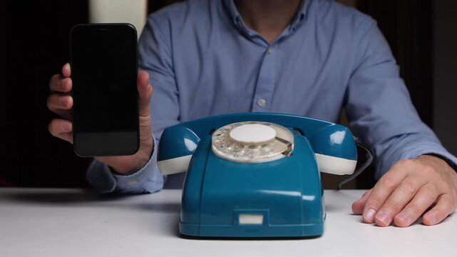 Modern versus vintage, Man displayed with antiquated and modern communication devices, Individual holding both modern mobile device and vintage rotary telephone showing technological differences