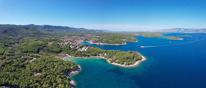 Aerial view of the vibrant town nestled among the verdant forests, contrasted against the deep blue sea and clear sky, Jelsa, Split-Dalmatia County, Croatia.