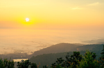 A beautiful winter landscape, with morning light filtering through the mist, mountains, and trees in the rural Phayao province in northern Thailand.