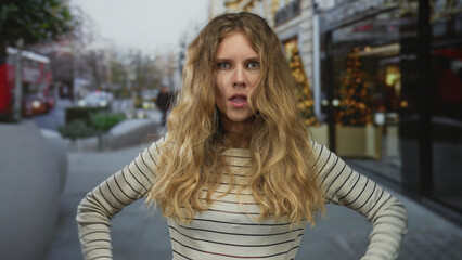Woman raises arms crossed on a street, conveying a blonde young persona to stop passing cars with a...