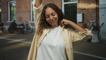 Woman hand covering face on street, one arm raised and eyes closed in a beige shirt, visible hand...