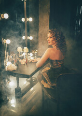 real person blonde hair retro lady sits at makeup table, mirror with vintage lamps. sexy woman burlesque show cabaret dancer actress, preparing make up. Flapper girl 20s roaring twenties old style