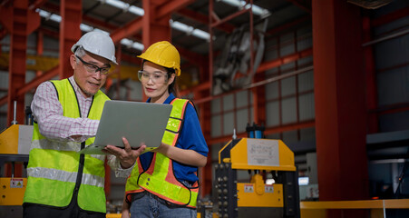 Engineer and technician inspecting materials on factory production line while discussing data on laptop. Great for industry, manufacturing, teamwork, and quality control concepts.