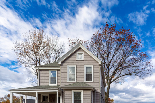 Charming classic American house with gray shake siding under a vibrant blue sky in Brighton, Boston, Massachusetts, USA
