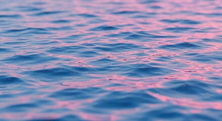 Gentle ripples on serene blue water surface reflecting soft pink sunset light