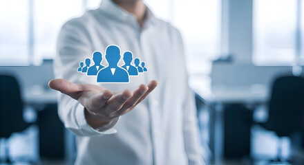 Man in white shirt holding hand out with blue people icons floating above palm in office setting with blurred background and natural light