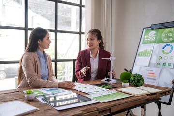 Businesswomen discussing esg sustainability concepts with wind turbine model