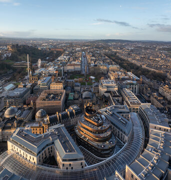 Aerial view of the intricate, modern architecture of the St James Quarter, contrasting with the distant silhouette of Edinburgh Castle, Edinburgh, Scotland, United Kingdom.