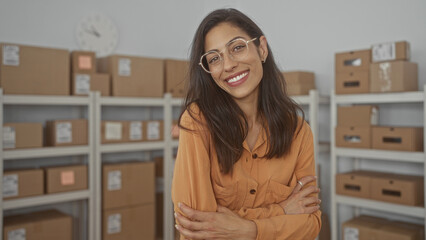 Woman with arms crossed among stacked parcel boxes on metal shelves in small storage building; rejection doubt.