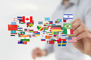 Concept of global interconnectedness, international relations, and worldwide unity. Hand holding floating flags of different countries, symboliz