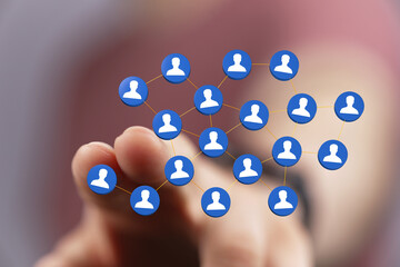 Hand reaching out to touch a network of people symbols, representing connection, communication, and social networking in a digital age.