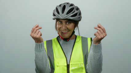 Hispanic senior woman wearing a helmet and reflective vest smiling with isolated white background, making gestures implying spending money.