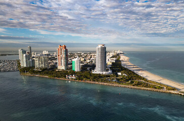 Fototapeta premium Aerial view of Miami city by the coast. Miami skyline with oceanfront skyscrapers. Scenic Miami panorama of Florida famous coastline. Drone shot of Miami above the shore.