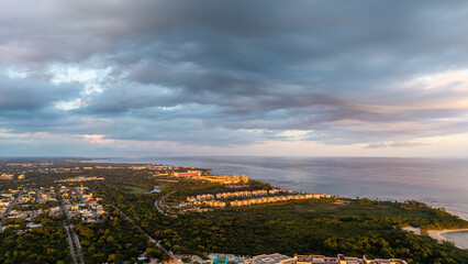Fototapeta premium Aerial drone view of coastline in playa del carmen at sunset with cloudy sky and orange warm lighting in summer 