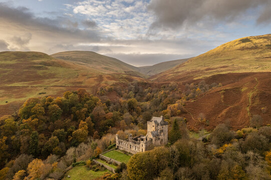 Aerial view of Castle Campbell nestled amidst the Ochil Hills, a symphony of autumnal hues under a vast sky, Dollar, Scotland, United Kingdom.