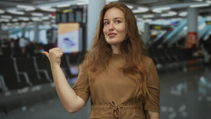 Woman with thumb pointing to side and finger to lips for silence in airport terminal lounge; anticipation.