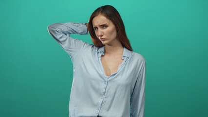 Fototapeta premium Redhead woman with hand behind head, furrowed brow, slightly exposed neckline and puzzled expression in studio; confusion.