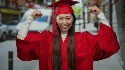 Woman in red graduation gown celebrating on urban street showcasing success and achievement in an academic setting.