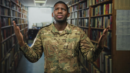 Soldier man in camouflage with pained face holding his upper arm and raised hands amid tall...