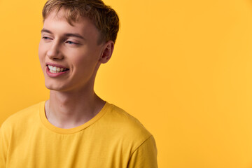 Smiling young man in a yellow tshirt against a bright yellow backdrop, casual and happy mood,...