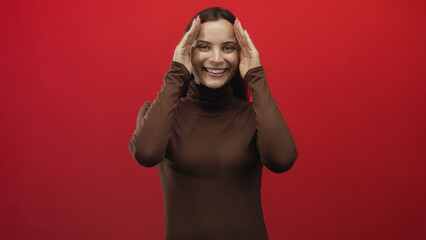 Woman wearing brown turtleneck covering face with both hands, palms pressed to eyes and furrowed...