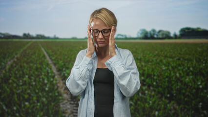 Woman in glasses presses hands to temples in apparent headache then folds palms as if praying in a...
