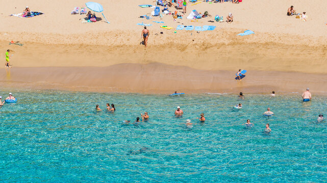 Aerial view of the beach with golden sands meeting the crystal-clear turquoise waters where swimmers enjoy a refreshing dip, Lahaina, Hawaii, United States.