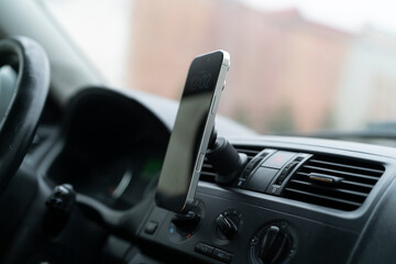 A phone holder is attached to the dashboard of a car as clouds fill the sky outside