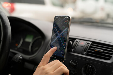 A person is using a smartphone to find directions while driving a car in traffic